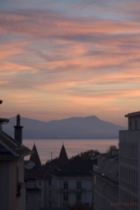 Un coucher de soleil sur les toits de Lausanne et le lac Léman.