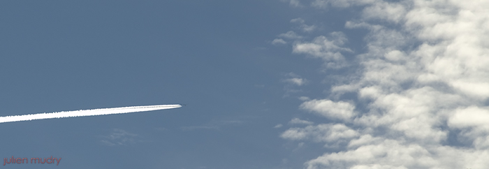 Un avion traversant un ciel blue se préparant à entrer dans des nuages.