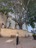 Sève Bernard sous un grand arbre se préparant pour le spectacle en attachant des ficelles de chanvre autour de son corps.