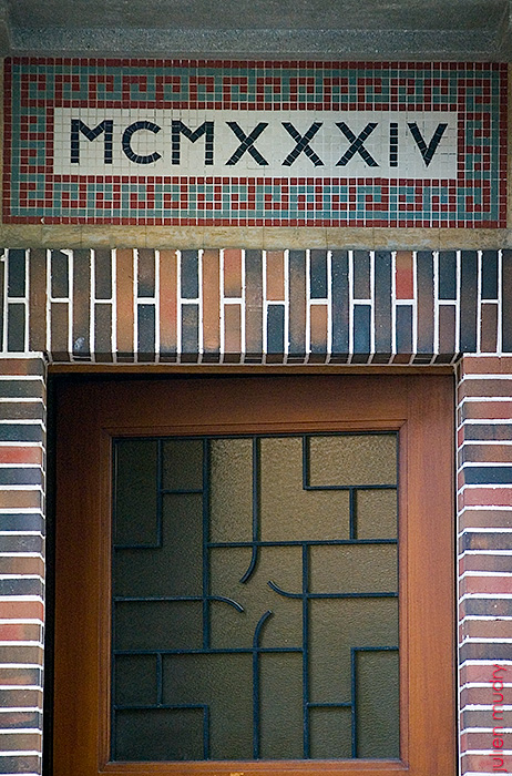 Une porte entrouverte avec MCMXXIV écrit en mosaïque au-dessus.